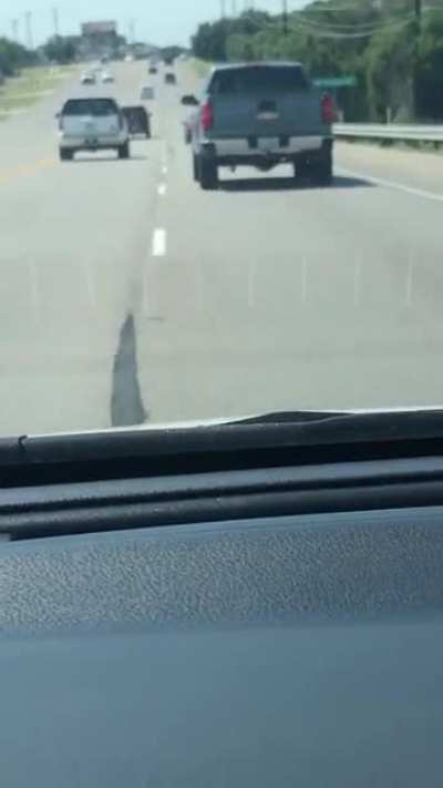 Black car harasses red landscaping truck for several minutes, yelling, brake checking, swerving, chasing, and throwing cans of soda at truck. Recording starts as truck decides he’s had enough and runs car off road.