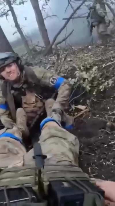 An American volunteer under fire helps his wounded Canadian comrade.

 Ukraine, February 2024.