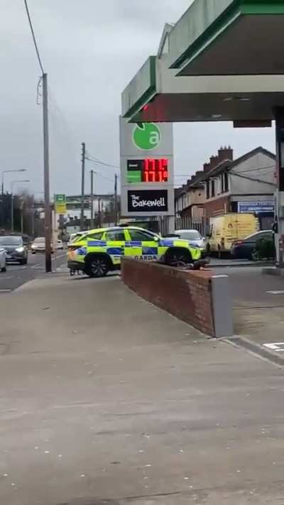 Dublin, Ireland. Man jumps from garage forecourt roof onto police car.