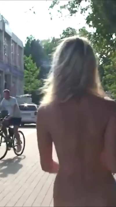 A naked blonde strolls along the embankment