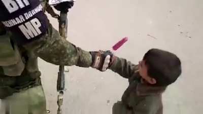 Russian soldier gives an ice pop to a Syrian boy