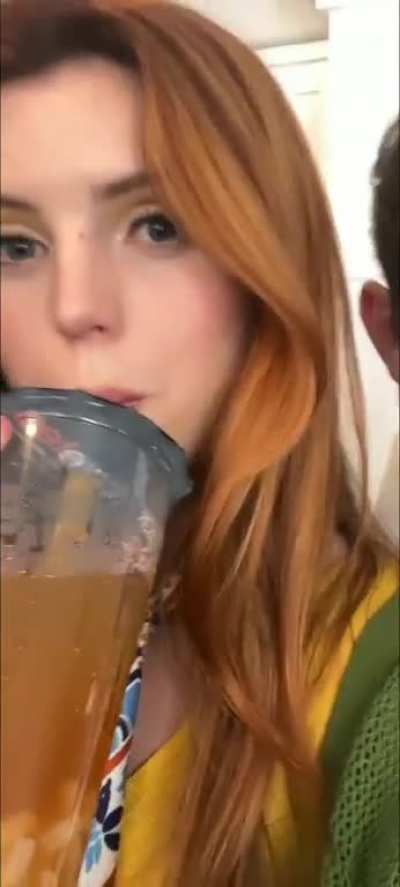 Sipping on her cold drink and doing a shoulder roll (June 2023)