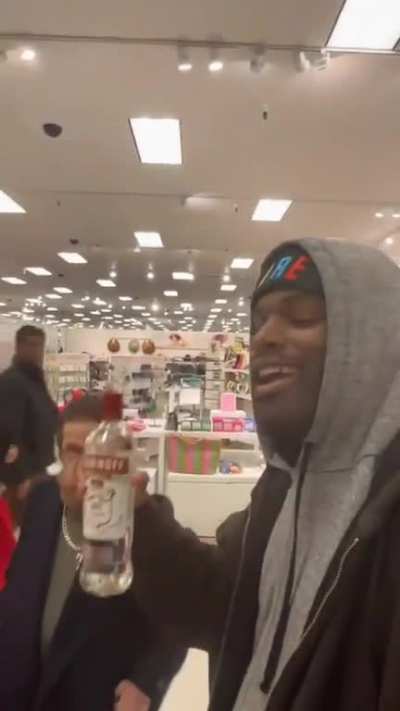 A kind man sharing a drink with another in the line to the cashier at Target.