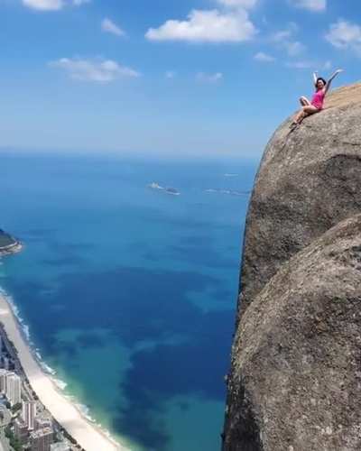 A tourist sitting on top of the Pedra da Gávea Mountain, Brazil