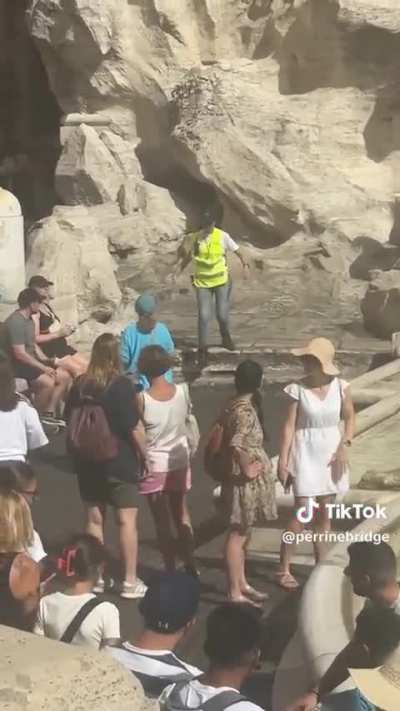 tourist fills her water bottle at Rome’s Trevi Fountain