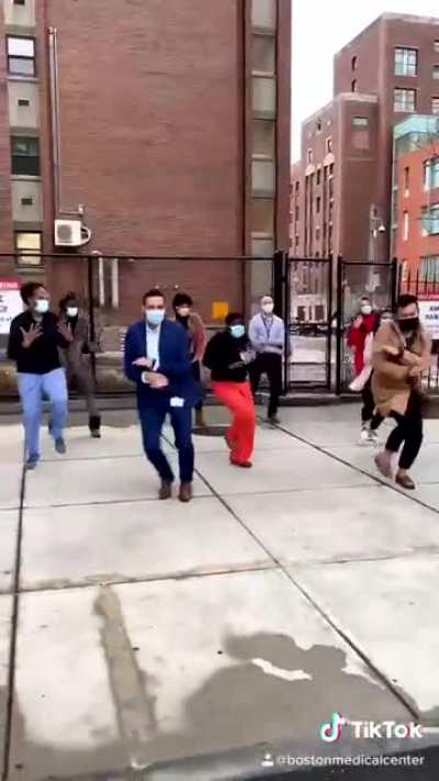 Boston health care workers dancing on the sidewalk to celebrate the arrival of the first covid-19 vaccine