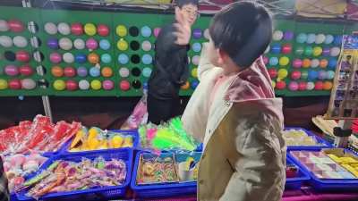 This kid is using a dart to pop balloons.