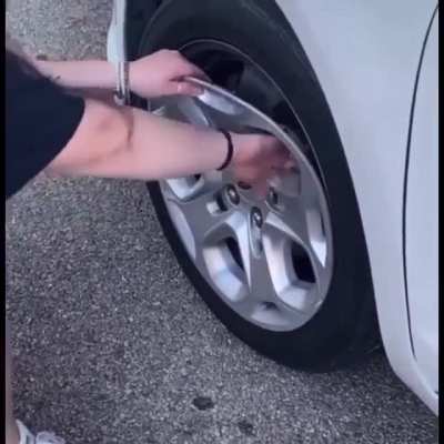 Woman tries to replace hubcaps by tearing off the old ones.