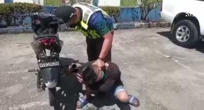 Cop holding a guy next to his loud bike after confiscating it for noise violations