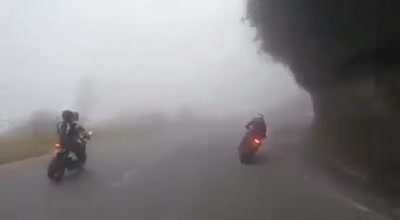 Group of motorcyclists speeding down a foggy mountain road, with very predictable results