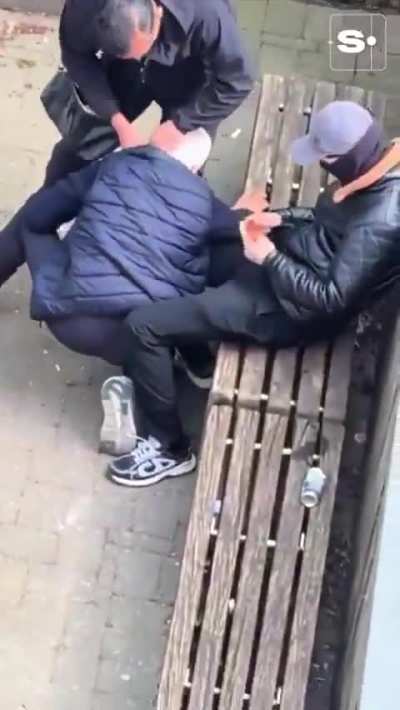 Two Belgian men strangle an old man in a bench next to a children's playground to rob him, leaving him unconscious. Nobody steps in to help