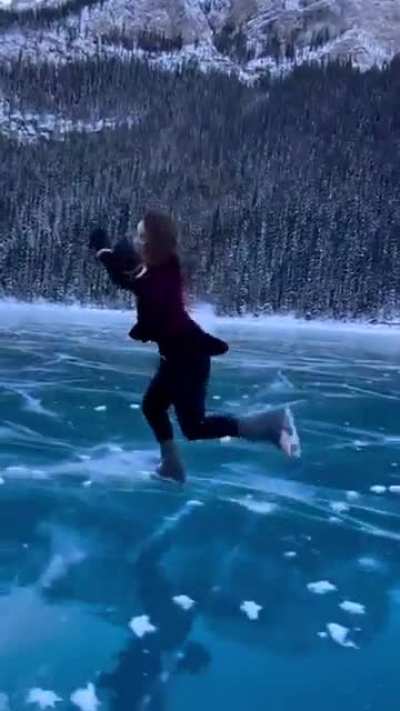 Lady skating on Lake Louise with magnificent mountains, perfectly tracked
