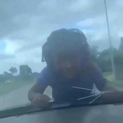 child hanging on to a car windshield going for a ride