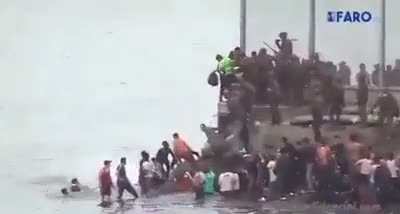 Spanish officers push people into sea as thousands of migrants cross border.