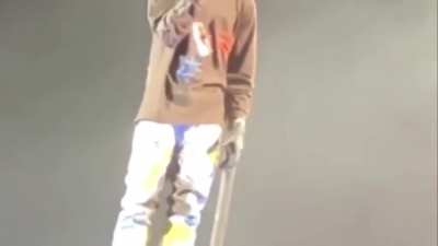 Travis Scott sings as he watches security carry away one of his fans lifeless body