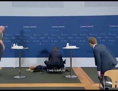 A Danish official passing out at a vaccination press conference.