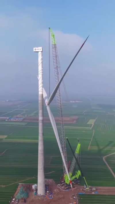 The sheer size of this wind turbine blade being hoisted into place by a crawler crane