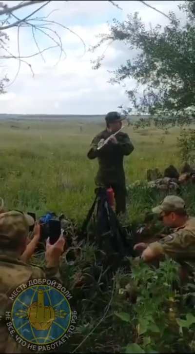 RU POV: Russian medic plays the flute for a group of soldiers while they are resting in the rear.