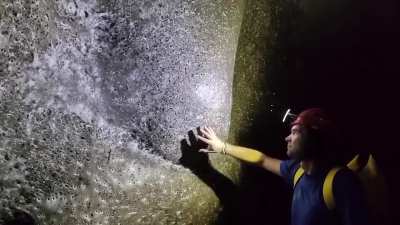Man touches the world's largest spiderweb, covering 106 m² in a sulfur cave on the Albania-Greece border