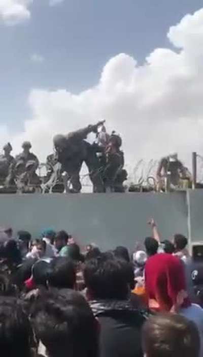 Toddler pulled over wall by U.S. soldiers as desperate crowds gather outside Kabul airport.
