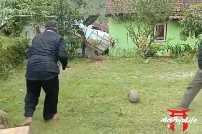 Man has accomplice throw a rock at his back to demonstrate Iron Body martial-arts skill (Pencak Silat, from Indonesia)