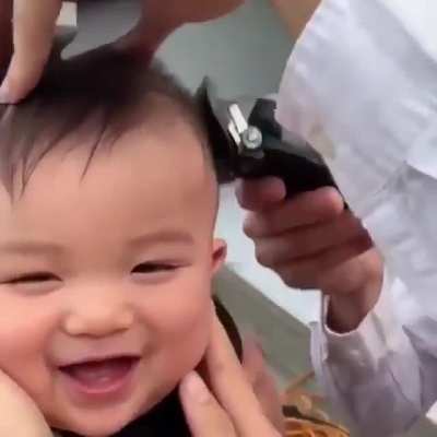 Giggling baby getting a haircut.