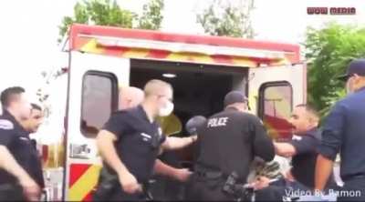 Cop punches a man on a stretcher being put in an ambulance