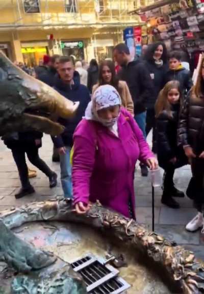 Cultural enricher steals tourists' money at the Porcellino fountain in Florence, Italy. Infinite degradation.