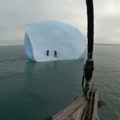Huge iceberg flipping with 2 people on it