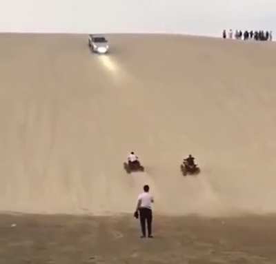 ATV race to the top of the sand dune.