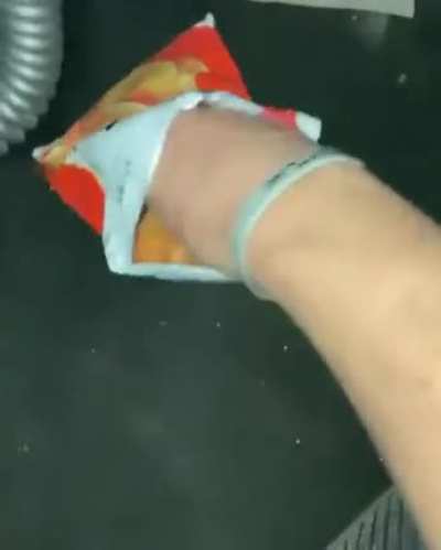 Man eats bag of chips while sitting inside a half-flooded car.