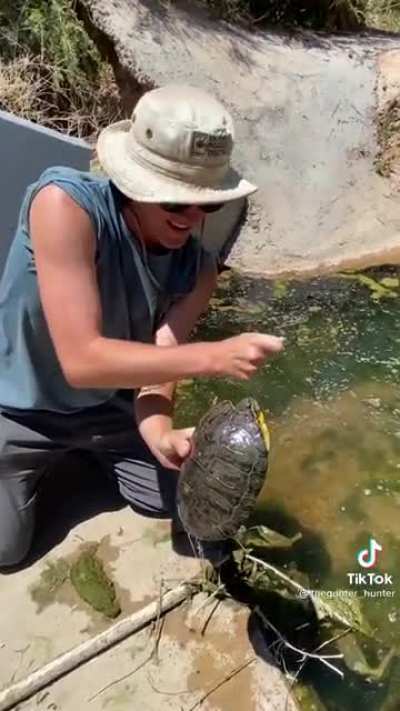 Idiot disturbs a red eared turtle and let’s it bite him