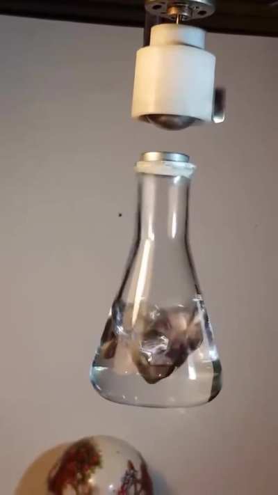 Motor speed ~3600 RPM (60 rev/s) matches the camera frame rate, freezing both the rotation and the flask’s oscillation, revealing their synch<wbr>roniz<wbr>ation in real time. A magnet trapped in air by a rotating dipole field.