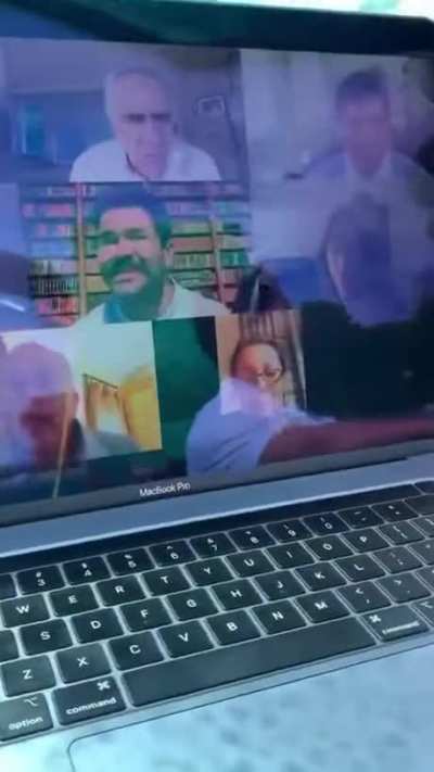 Guy is on a zoom call with a green screen to make it look like he's at home.