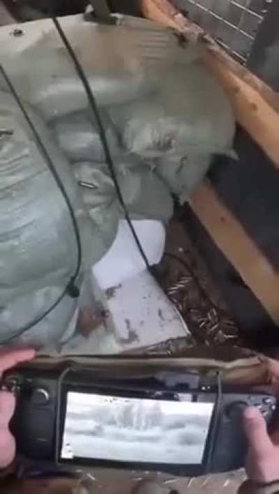 Ukrainian soldier remote operating a machine gun with a Steam Deck gaming system.