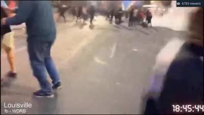 People throw objects at Louisville police as they come out to extinguish a fire outside of the courthouse