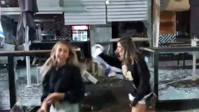 Two Israeli girls celebrating in front of a vandalized store