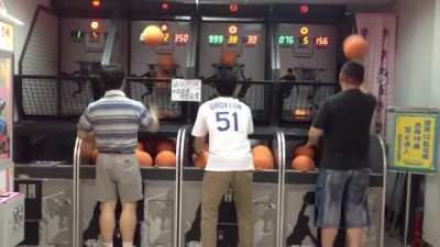 Asian dad locked in on a basketball arcade game