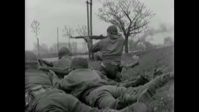 A confusing and slightly amusing scene as a few German troops try to surrender as American and German troops exchange fire. Altenburg, Germany. April 1945.