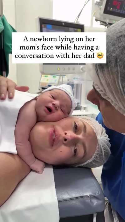A heartwarming video shows a newborn baby lying on her mother's face while having a sweet little conversation with her dad. A pure moment of love that melted hearts across the internet