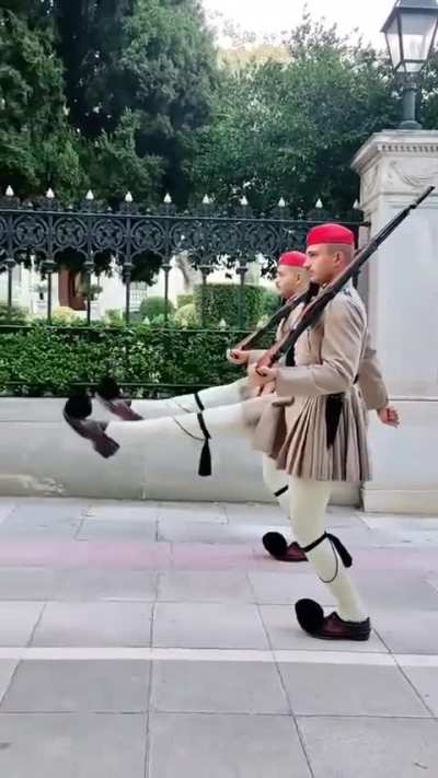 The Evzones are the Presidential Guard of Greece. An evzone must stand at least 1.87 meters tall, it’s preferable for their knees to touch as they stand upright, and they must be fit enough to raise their legs to shoulder height, completely straight, as t