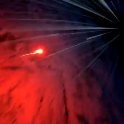Man ties some sort of flare gun to his feet and jumps off a cliff in a wingsuit looking like a comet.