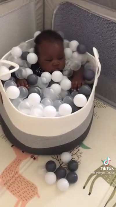 Dad puts baby in a ball pit, baby is not amused