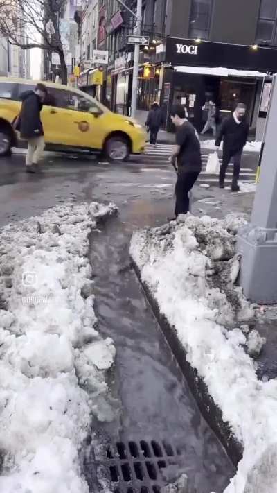 man clears snow to help people cross street