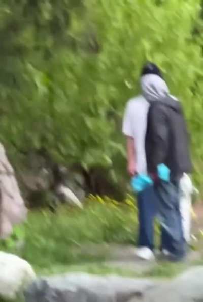 Man with a dog (and a fish?) antagonizing a black bear despite bystanders yelling.
