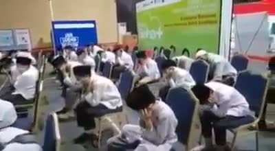 Indonesian Islamic school students closing their ears when music plays in a covid vaccination queue
