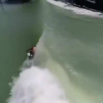 Surfer catching waves created by train.