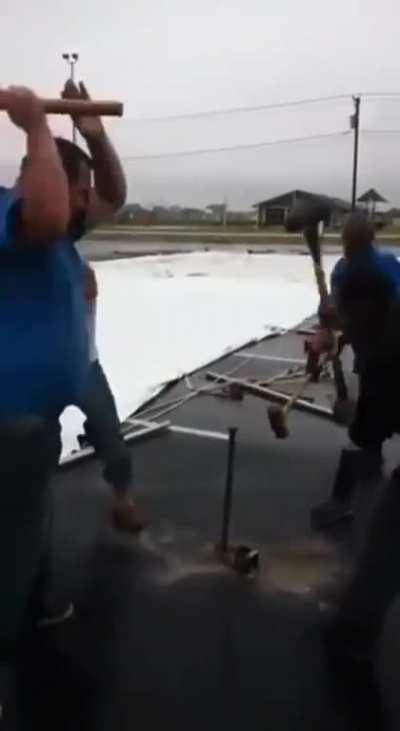 4 men rhythmically pounding a hard steel rod deep into the ground.