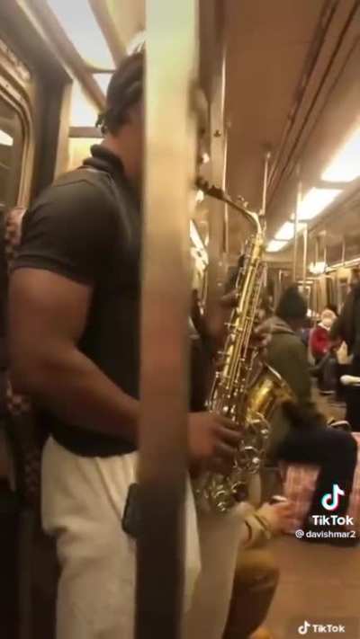 Guy plays the sax while people argue behind him
