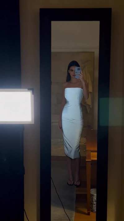 Checking herself out in a white dress